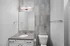 Modern bathroom with sleek design, featuring a stylish vanity, large mirror, and contemporary light fixture.