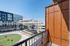 Modern apartment balcony overlooking a vibrant urban plaza with green space and public seating, perfect for city views and lifestyle amenities.