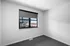 Bright, modern room with large window and sleek carpet flooring, offering a stylish and cozy living space.