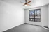 Bright empty room featuring modern ceiling fan, large window with city view, and cozy carpet flooring.