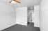 Contemporary room with sleek ceiling fan, grey carpeting, and access to a modern bathroom featuring clean lines and minimalist design.