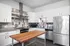 Modern kitchen featuring sleek stainless steel appliances, white cabinetry, and a chic wooden island accenting the contemporary tile backsplash.