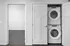 Modern apartment with in-unit stacked washer and dryer next to a cozy carpeted room.