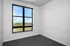 Bright room with a large window offering stunning views of greenery and cityscape, perfect for a cozy home office or bedroom.