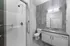 Modern and sleek bathroom featuring elegant gray tiles, a stylish vanity with ample storage, and a spacious walk-in shower.
