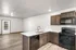 Modern apartment kitchen with sleek dark cabinets, stainless steel appliances, and an open-concept layout leading to a bright living area.