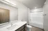 Modern bathroom with sleek white fixtures, elegant vanity, and spacious bathtub for ultimate comfort.