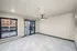 Modern apartment interior featuring a spacious living area with marble-like flooring, large windows, and a ceiling fan, offering natural light and city views.