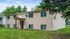 Charming suburban home with beige siding, lush green lawn, and mature trees creating a peaceful atmosphere.