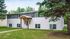 Charming two-story apartment building surrounded by lush greenery, featuring a welcoming entrance and ample natural light.