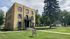 Charming three-story brick apartment building with classic architecture, lush green lawn, and cozy outdoor seating. Ideal location for vibrant living surrounded by tree-lined streets.