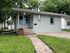 Charming single-story home with a cozy front porch, surrounded by lush greenery, perfect for serene living.