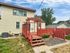 Charming backyard with a red wooden deck and pergola, perfect for outdoor gatherings and relaxation.
