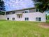 Charming suburban apartment building with a lush green lawn and a welcoming entrance.
