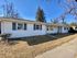 Charming ranch-style home with white siding, blue shutters, and a welcoming front porch on a sunny day.