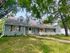 Charming blue suburban home with lush greenery and white picket fence, offering a welcoming and serene atmosphere.