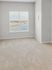 Bright and spacious room with plush carpet and large window overlooking serene water view.