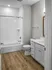 Modern bathroom with sleek white tile, elegant vanity, and warm wooden flooring, offering a stylish and functional space.