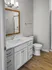 Modern bathroom featuring a sleek vanity with a white countertop, elegant lighting, and wood-style flooring.