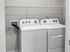Modern laundry room featuring sleek washer and dryer with convenient shelving above.