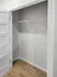 Spacious empty closet with sleek white shelving and a modern white door, offering ample storage potential.