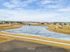 Idyllic suburban view with scenic lake, walking trails, and nearby modern homes under a bright blue sky.