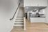 Modern apartment showcasing a chic open kitchen with sleek appliances, inviting staircase, and warm wood flooring.