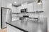 Modern kitchen with sleek black countertops, stainless steel appliances, and elegant white cabinetry.