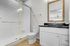 Modern bathroom featuring sleek white cabinetry, elegant framed mirror, and a chic glass-enclosed shower with white subway tiles.