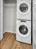 Modern laundry area with stacked washer and dryer, featuring sleek design and efficient use of space on stylish wooden flooring.
