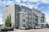 Modern apartment building with sleek gray exterior, large windows, and balconies, offering convenient urban living with ample parking.