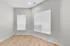 Elegant corner room with two large windows offering ample natural light, featuring sleek hardwood flooring and soft gray walls for a modern touch.