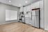 Modern kitchen with sleek stainless steel appliances, white cabinetry, and elegant wood flooring.