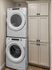Modern laundry area with stacked washer and dryer alongside elegant storage cabinets.
