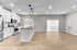 Modern open-plan kitchen with sleek cabinets, stainless steel appliances, and elegant pendant lighting, leading into a spacious living area with natural wood flooring and abundant natural light.