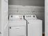 Modern laundry area with high-efficiency washer and dryer, featuring ample shelving for storage.