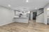 Contemporary open-plan kitchen featuring sleek white cabinets, stainless steel appliances, and elegant pendant lighting, complemented by warm hardwood floors.