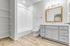 Bright and modern bathroom featuring elegant white subway tile, spacious vanity with sleek cabinetry, and stylish wood-look flooring.