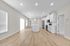 Modern open-plan kitchen and living area with sleek white cabinetry, central island, and stylish wood flooring.