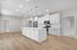 Modern kitchen with sleek white cabinetry, spacious island, and stainless steel appliances, enhanced by elegant pendant lighting.