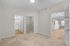 Inviting bedroom featuring plush carpet, connecting to a sleek bathroom, spacious walk-in closet, and open-concept kitchen with modern lighting.