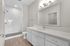 Elegant bathroom with a modern white vanity and spacious walk-in shower, featuring subway tile and sleek fixtures.