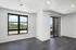 Bright modern room with large windows and balcony access, featuring sleek wood flooring and neutral walls.