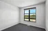 Bright, spacious bedroom with a large window offering stunning views of lush greenery and blue skies.