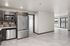 Modern kitchen with stainless steel appliances leading to a bright, open living space with balcony views.