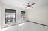 Bright and spacious room with modern ceiling fan, large windows offering city views, and elegant tile flooring.