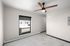 Contemporary apartment interior featuring a bright room with a modern ceiling fan and large window for natural light.