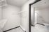 Modern walk-in closet with sleek white shelving adjoining a pristine bathroom featuring elegant tile flooring.