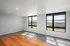 Bright and spacious living area with large windows offering scenic views, featuring modern flooring and a fresh, contemporary design.