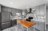 Modern kitchen with sleek gray cabinetry, stainless steel appliances, and a stylish wooden island against a chic tiled backsplash.